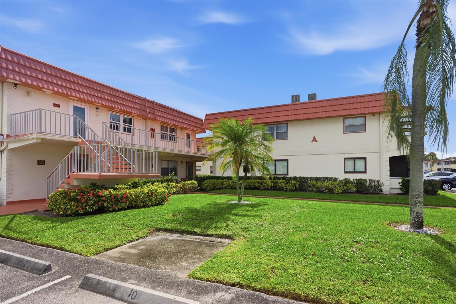 A two-story apartment building with a red tile roof and a central grassy courtyard — 47 Saxony A, Delray Beach FL 33446, DELRAY BEACH, FL
