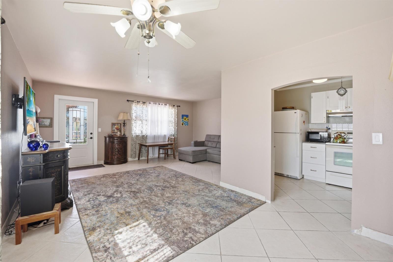 An open-concept living room with tile floors leads into a white kitchen through an archway — 47 Saxony A, Delray Beach FL 33446, DELRAY BEACH, FL