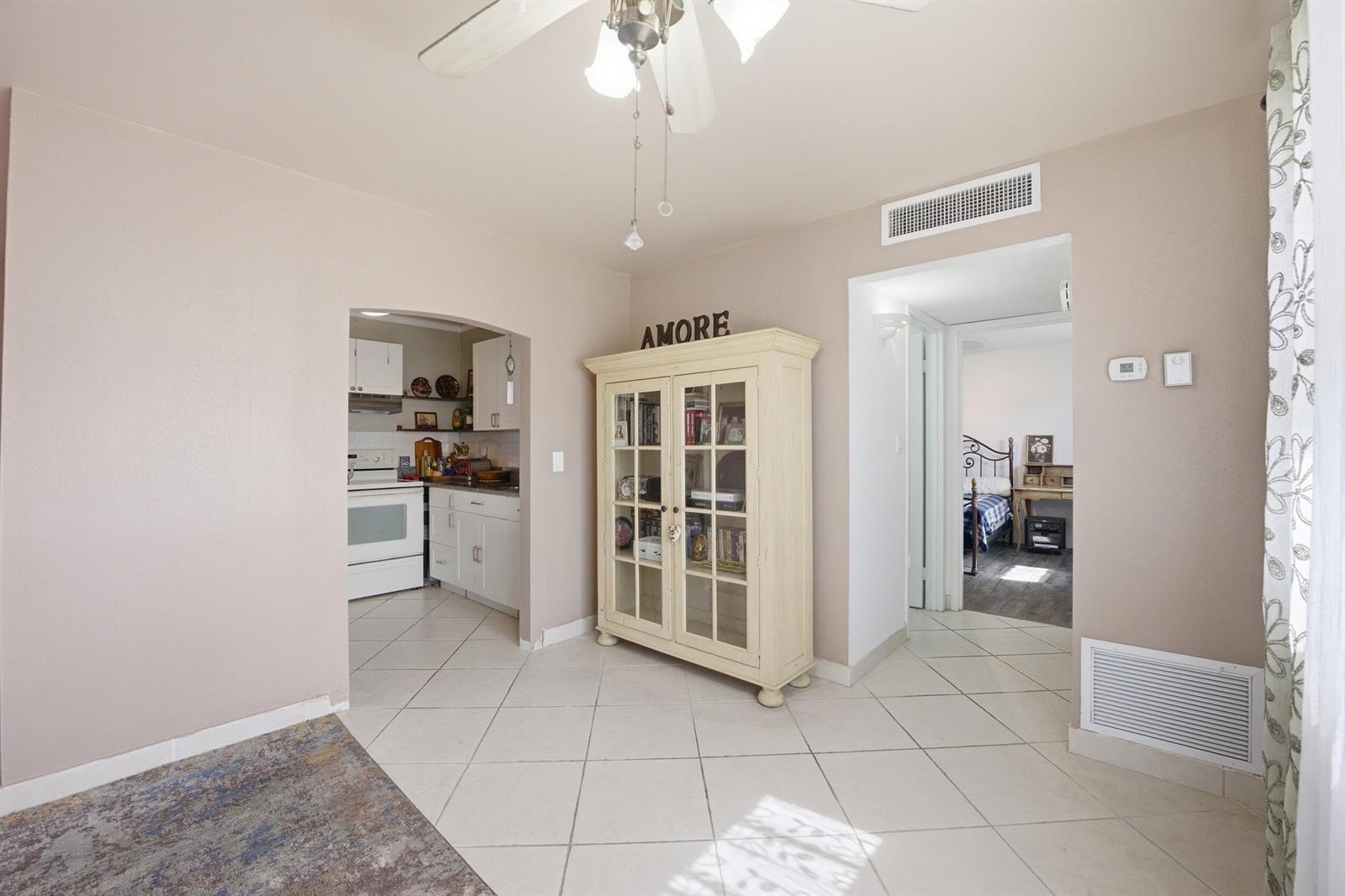 A living area with tile floors, a cream-colored display cabinet, and an arched kitchen entrance — 47 Saxony A, Delray Beach FL 33446, DELRAY BEACH, FL