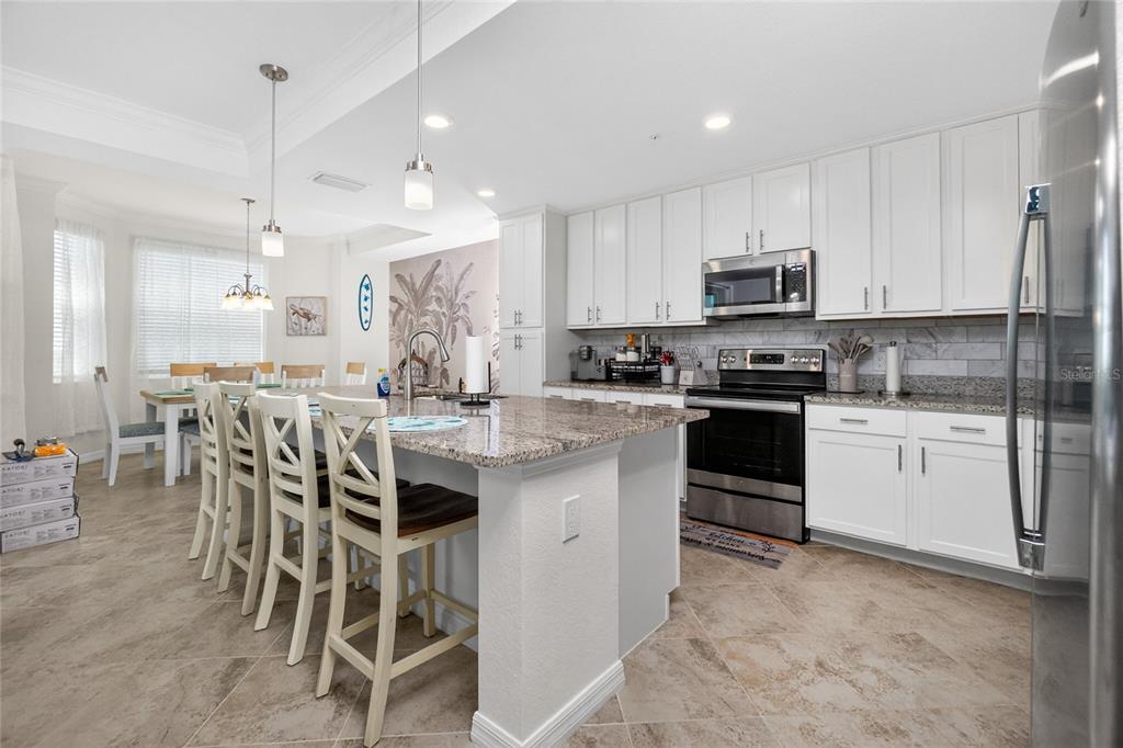 A kitchen features white cabinets, granite countertops, a large island, and an adjacent dining area — 14081 HERITAGE LANDING BOULEVARD UNIT 232, PUNTA GORDA, FL