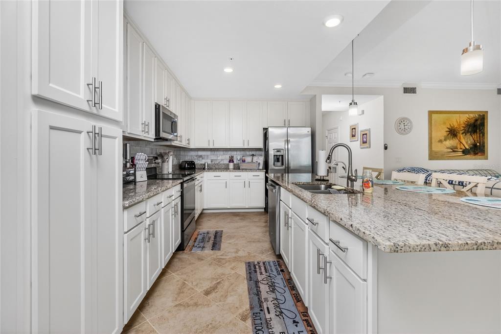 A kitchen features white cabinets, granite countertops, stainless steel appliances, and a large island — 14081 HERITAGE LANDING BOULEVARD UNIT 232, PUNTA GORDA, FL