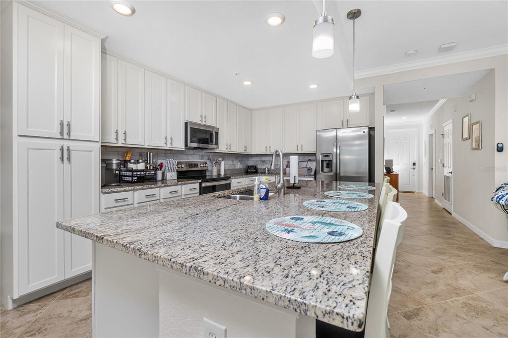 A kitchen features white cabinetry, granite countertops, a large island, and stainless steel appliances — 14081 HERITAGE LANDING BOULEVARD UNIT 232, PUNTA GORDA, FL