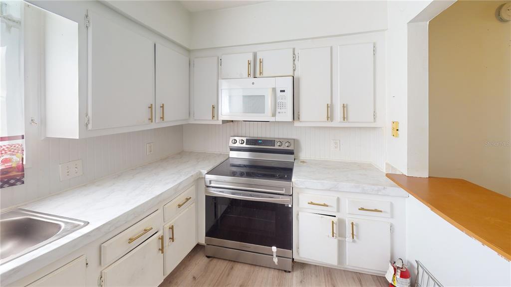 A kitchen features white cabinets, stainless steel appliances, and light-colored laminate countertops — 4030 CORTEZ DRIVE UNIT B, TAMPA, FL
