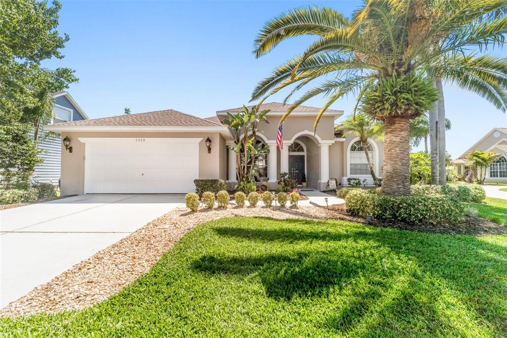 A single-story house with a white garage, arched entryway, and a large palm tree — 1819 LATELIA COURT, TRINITY, FL