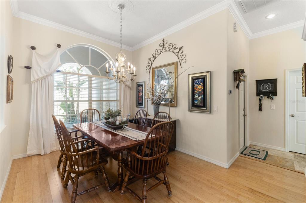 A dining room features a wooden table, spindle chairs, a chandelier, and a large window — 1819 LATELIA COURT, TRINITY, FL