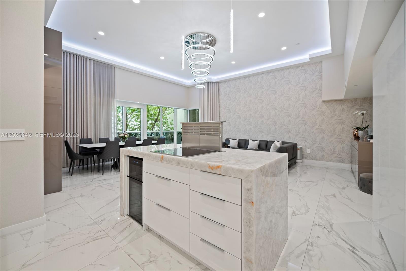 A modern kitchen features a marble-topped island with a pop-up vent and white cabinetry — 1800 S Ocean Dr # 310, Hallandale Beach FL 33009, HALLANDALE BEACH, FL