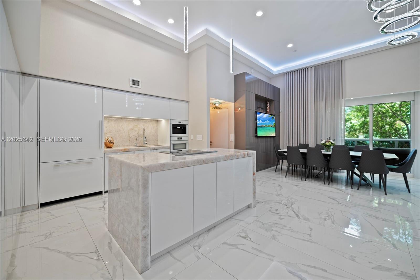 A modern kitchen and dining area feature white cabinetry, marble countertops, and large floor tiles — 1800 S Ocean Dr # 310, Hallandale Beach FL 33009, HALLANDALE BEACH, FL