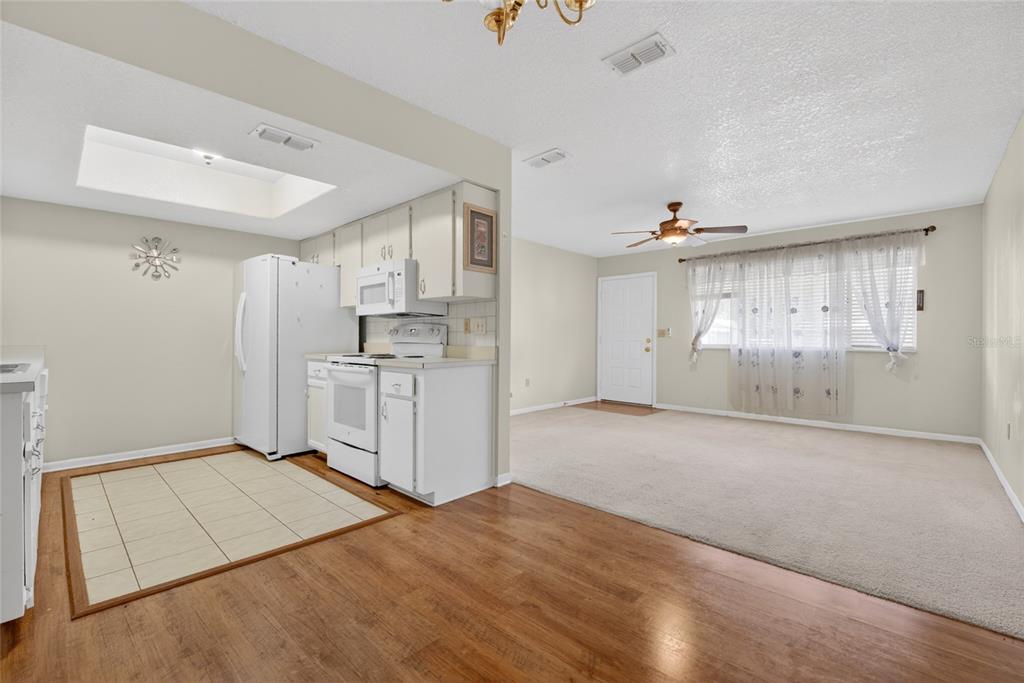 A kitchen with white appliances and cabinets opens into a carpeted living area — 8720 SW 108TH LANE, OCALA, FL