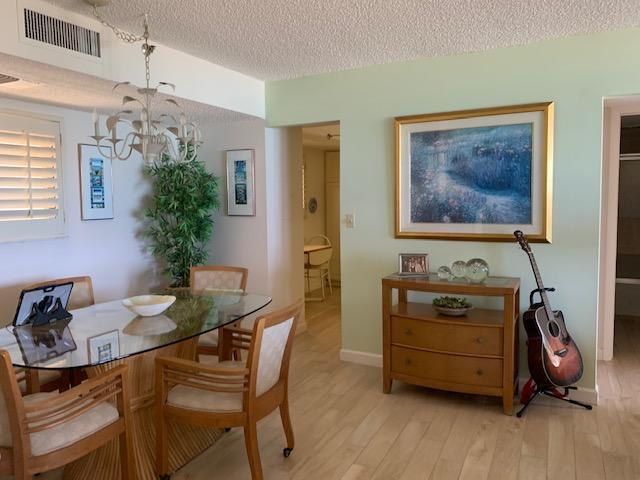 A dining area features a glass table, wooden chairs, a chandelier, and a wooden console table — 300 Ocean Trail Way # 602, Jupiter FL 33477, JUPITER, FL