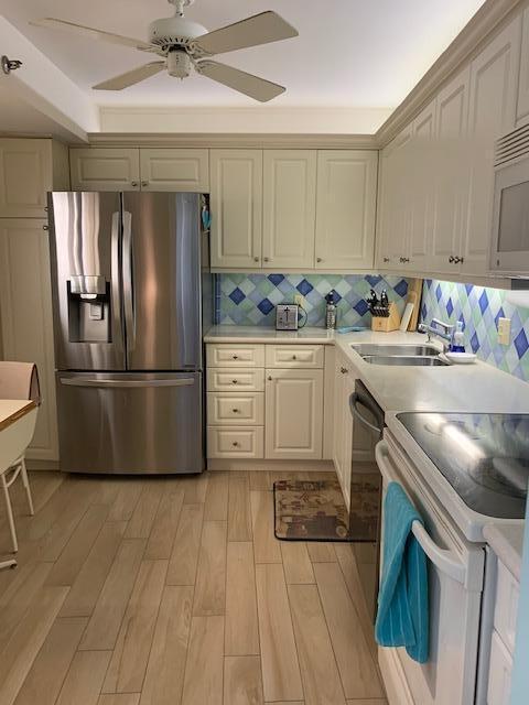 A kitchen with cream-colored cabinets, stainless steel appliances, and a blue and white diamond-patterned backsplash — 300 Ocean Trail Way # 602, Jupiter FL 33477, JUPITER, FL