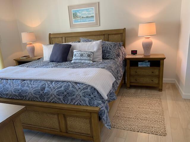 A bedroom features a wooden bed with a blue patterned comforter and matching nightstands — 300 Ocean Trail Way # 602, Jupiter FL 33477, JUPITER, FL