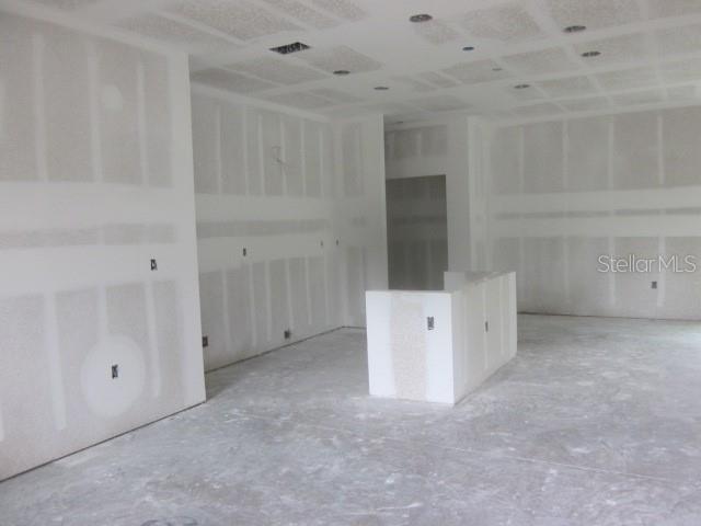 An unfinished room features drywall walls and ceiling with recessed lighting and a central island — 15456 PIEDMONT AVENUE, PORT CHARLOTTE, FL