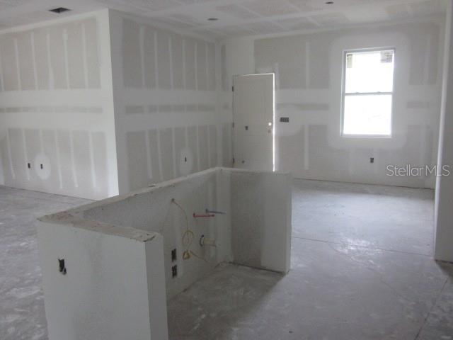 An unfinished room features drywall, a kitchen island base with plumbing, and a single window — 15456 PIEDMONT AVENUE, PORT CHARLOTTE, FL
