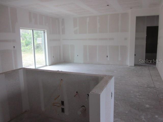 An unfinished room with drywall, a sliding glass door, and a kitchen island frame — 15456 PIEDMONT AVENUE, PORT CHARLOTTE, FL
