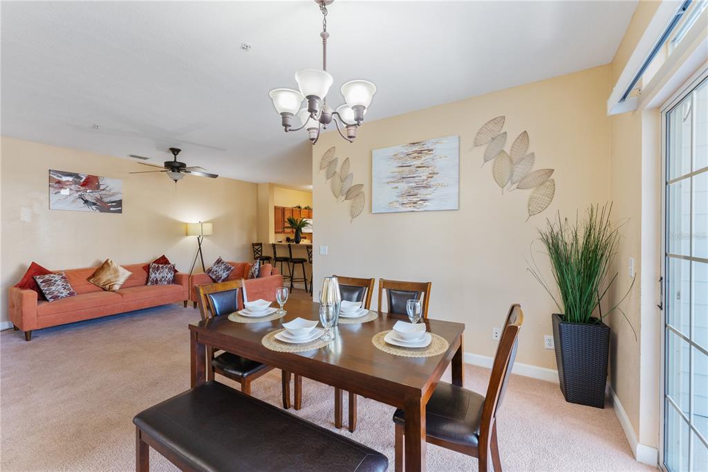 A dining area with a wooden table and chairs sits in front of a living room — 3174 FELTRIM PLACE UNIT 201, KISSIMMEE, FL