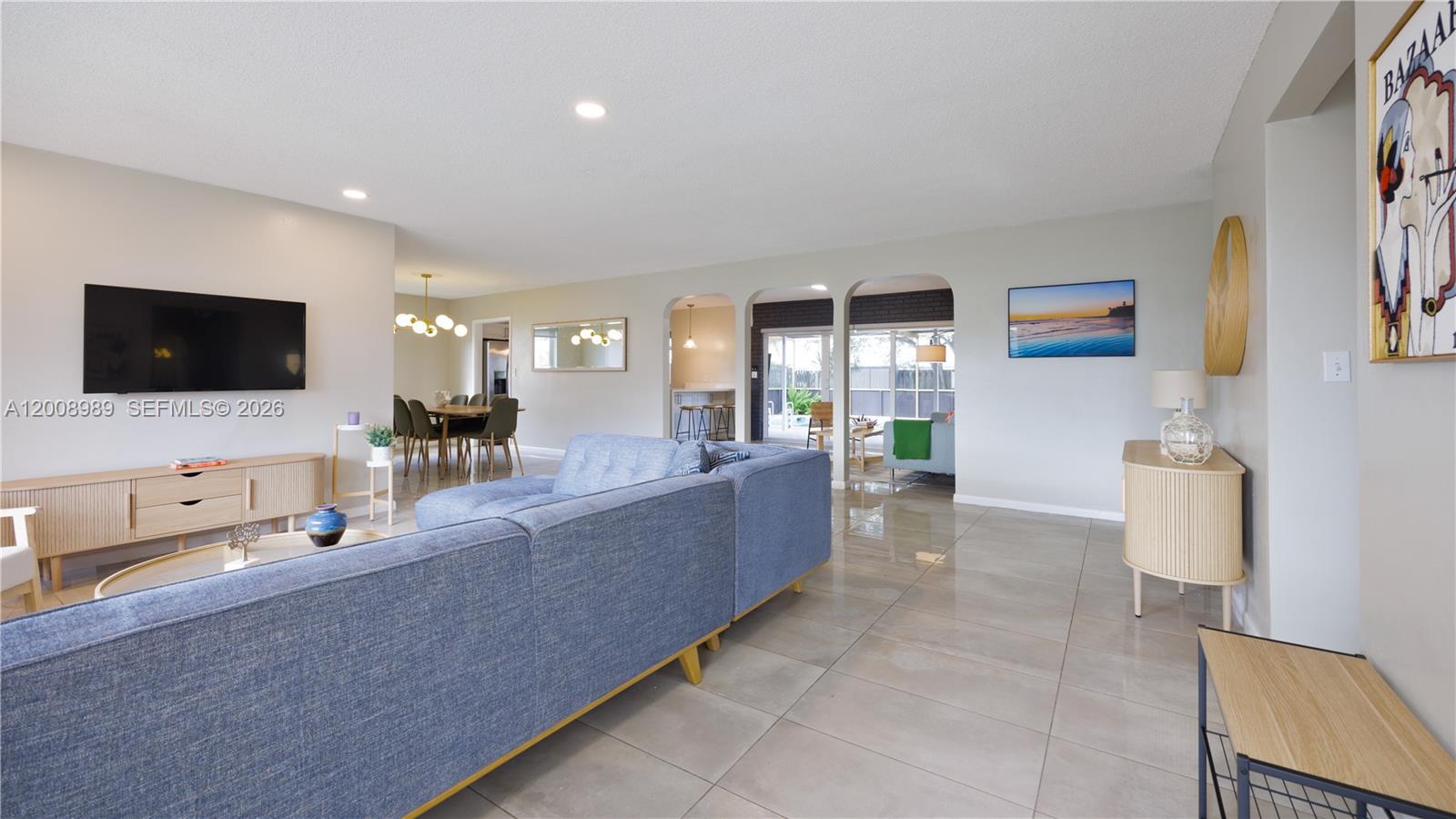 A living room features a blue sectional sofa, light tile flooring, and arched doorways — 609 S Crescent Dr, Hollywood FL 33021, HOLLYWOOD, FL