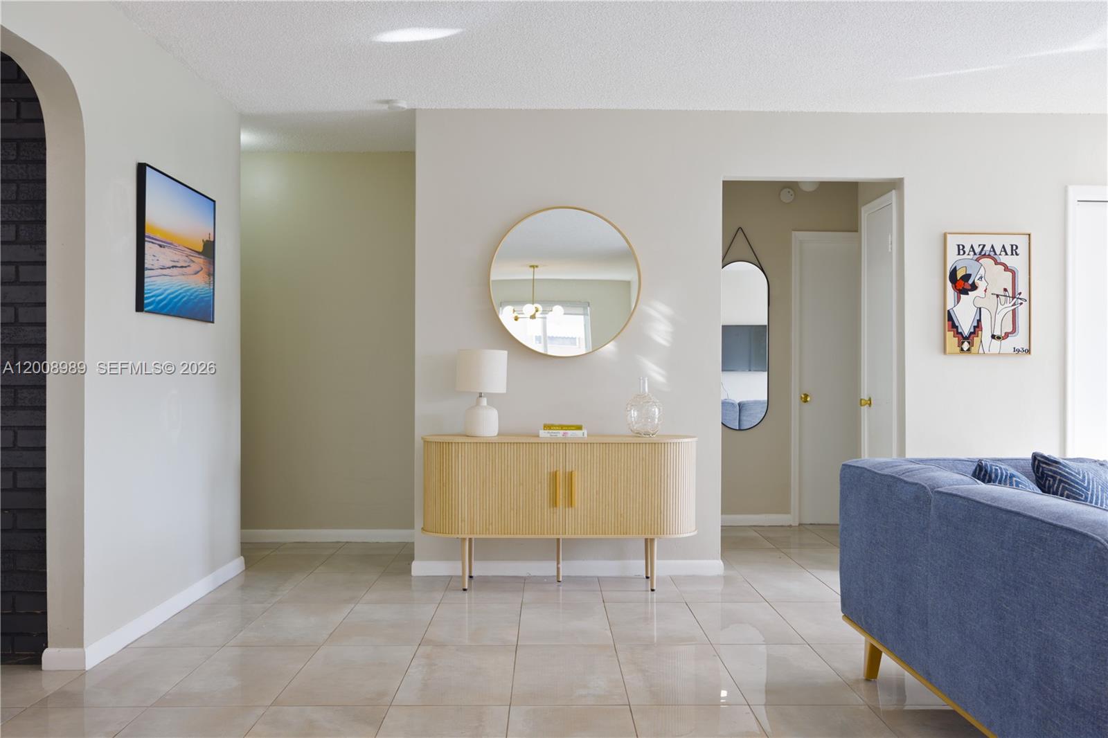 A light-colored hallway features a wooden console table, a round mirror, and tile flooring — 609 S Crescent Dr, Hollywood FL 33021, HOLLYWOOD, FL