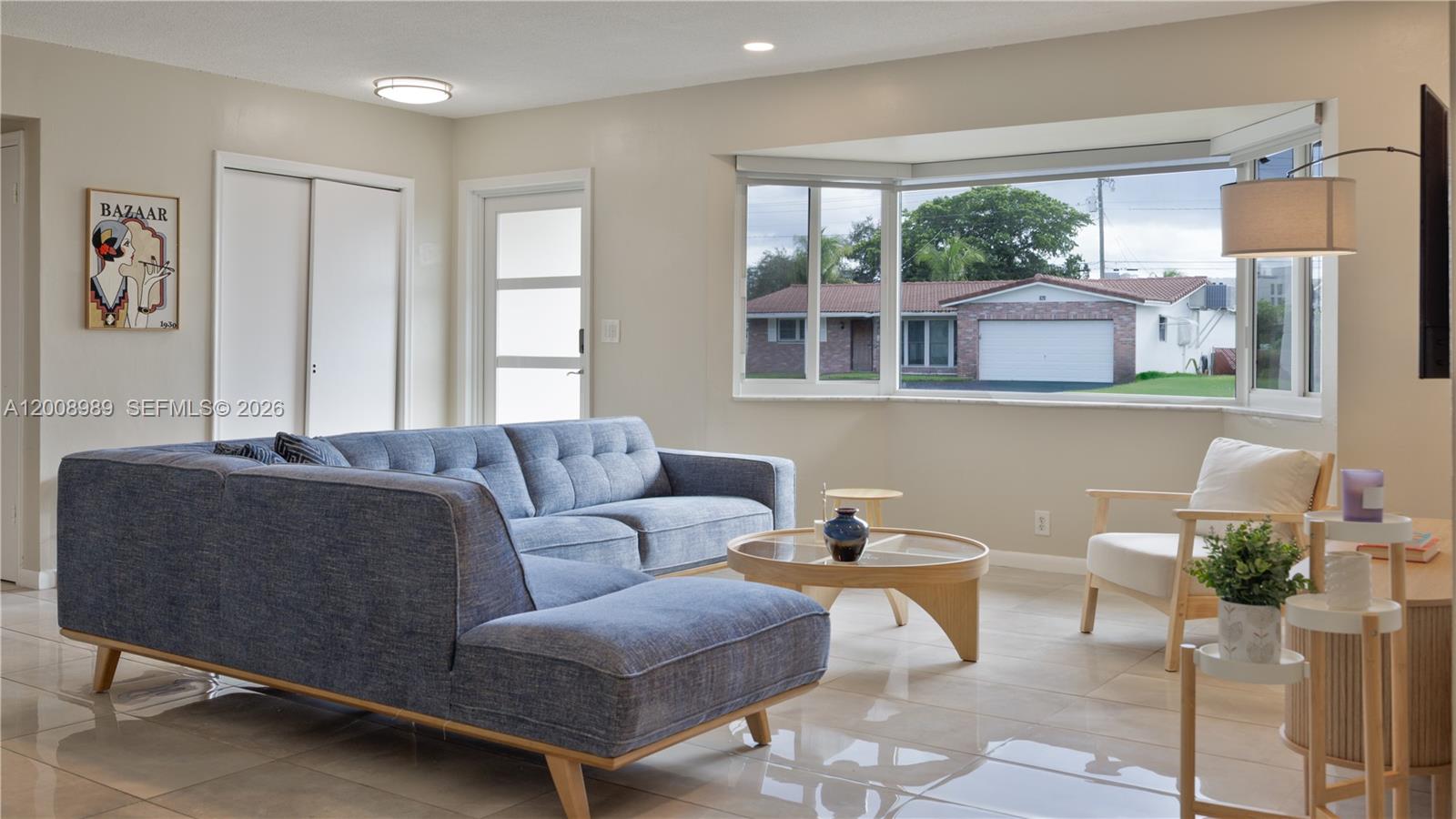 A living room features a blue sectional sofa, a round coffee table, and a bay window — 609 S Crescent Dr, Hollywood FL 33021, HOLLYWOOD, FL
