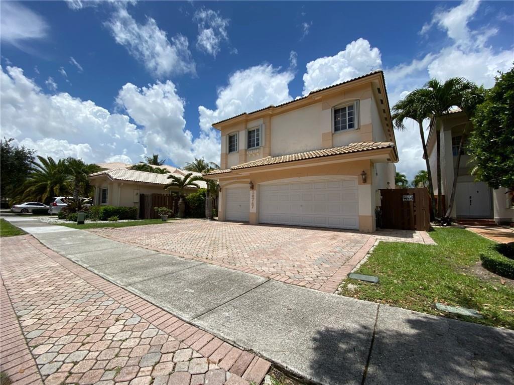 A two-story house with a paved driveway and a three-car garage under a cloudy sky — 10747 NW 70th Terrace, Doral FL 33178, DORAL, FL