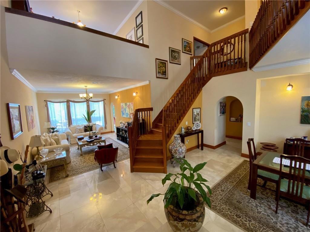 A two-story foyer features a wooden staircase, tile flooring, and an open living area — 10747 NW 70th Terrace, Doral FL 33178, DORAL, FL