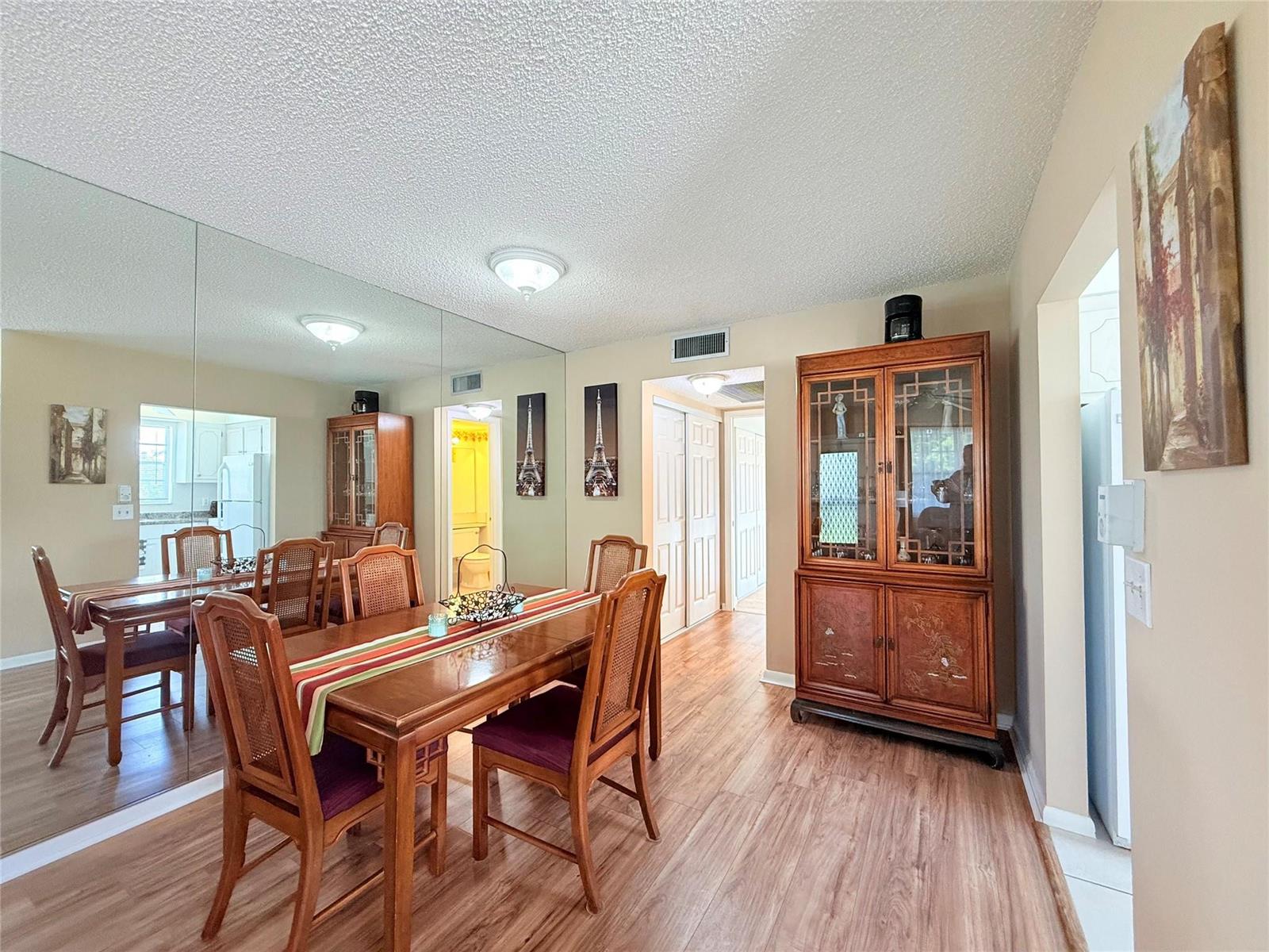 A dining room features a wooden table with chairs, a large wall mirror, and flooring — 204 Oakridge M # 204, Deerfield Beach FL 33442, DEERFIELD BEACH, FL