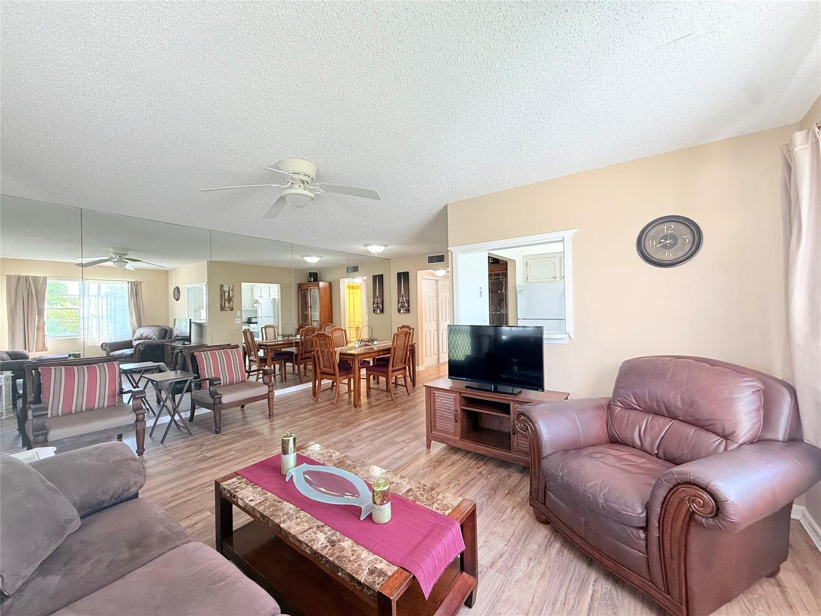 A living room with wood-look flooring, a mirrored wall, and a leather armchair — 204 Oakridge M # 204, Deerfield Beach FL 33442, DEERFIELD BEACH, FL