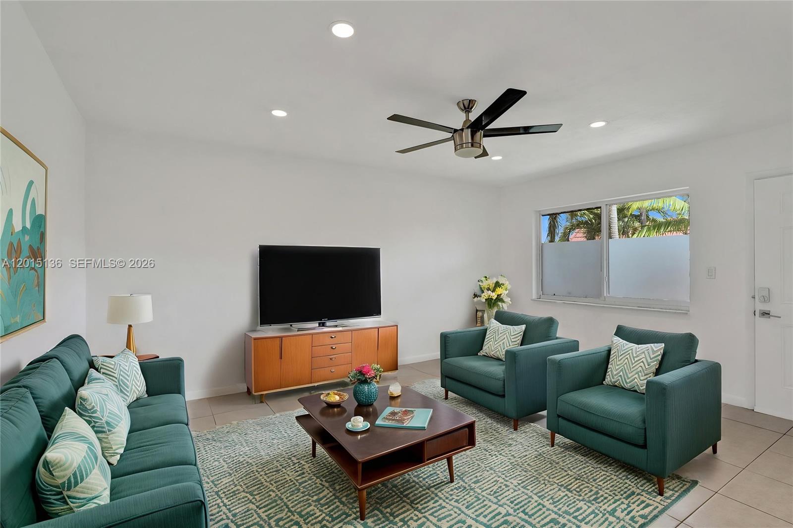 A living room features teal furniture, a wooden media console, and a dark coffee table — 3050 NE 5th Ter # 13, Wilton Manors FL 33334, WILTON MANORS, FL