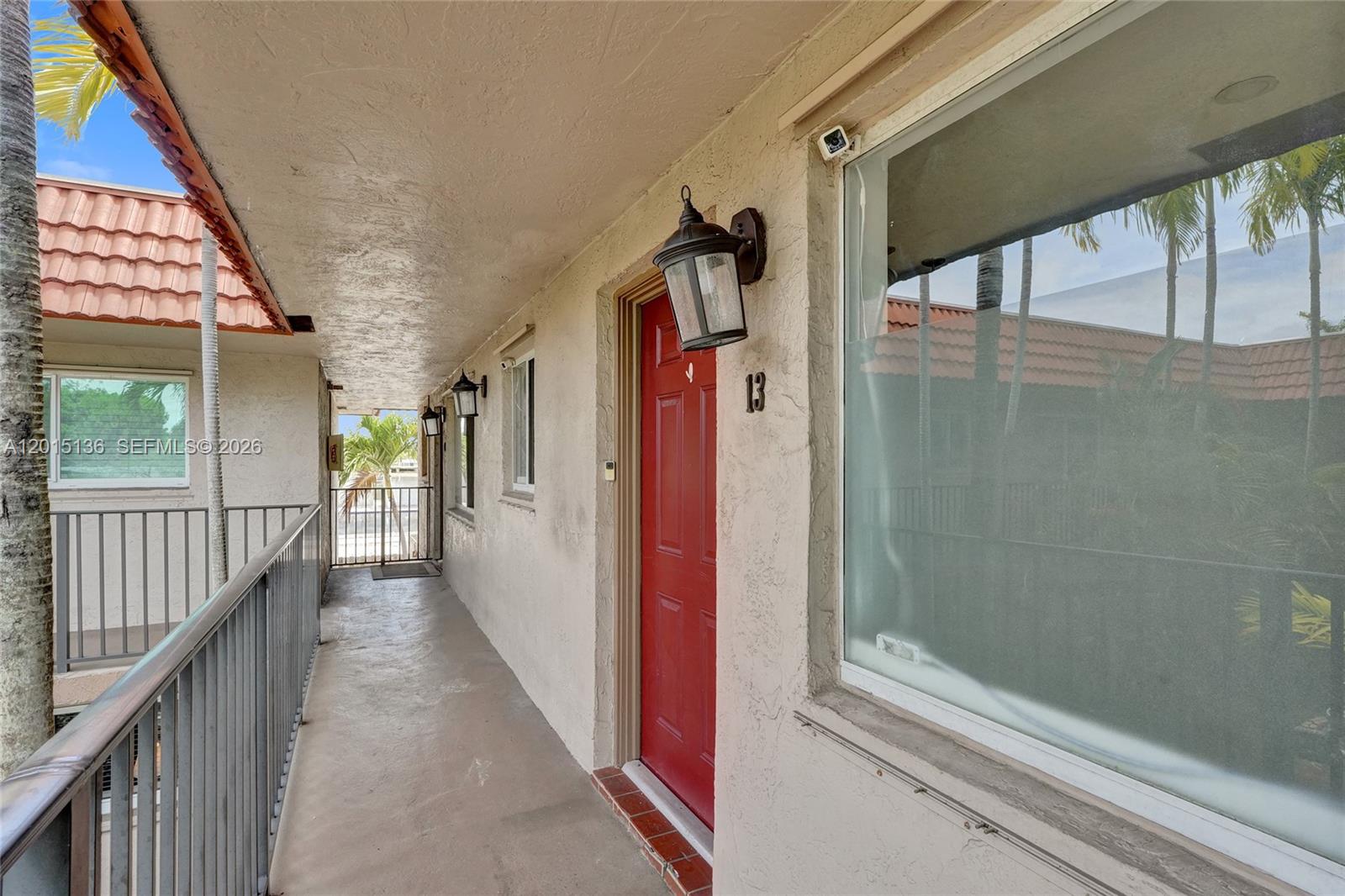 An exterior walkway leads to a red front door marked with the number 13 — 3050 NE 5th Ter # 13, Wilton Manors FL 33334, WILTON MANORS, FL