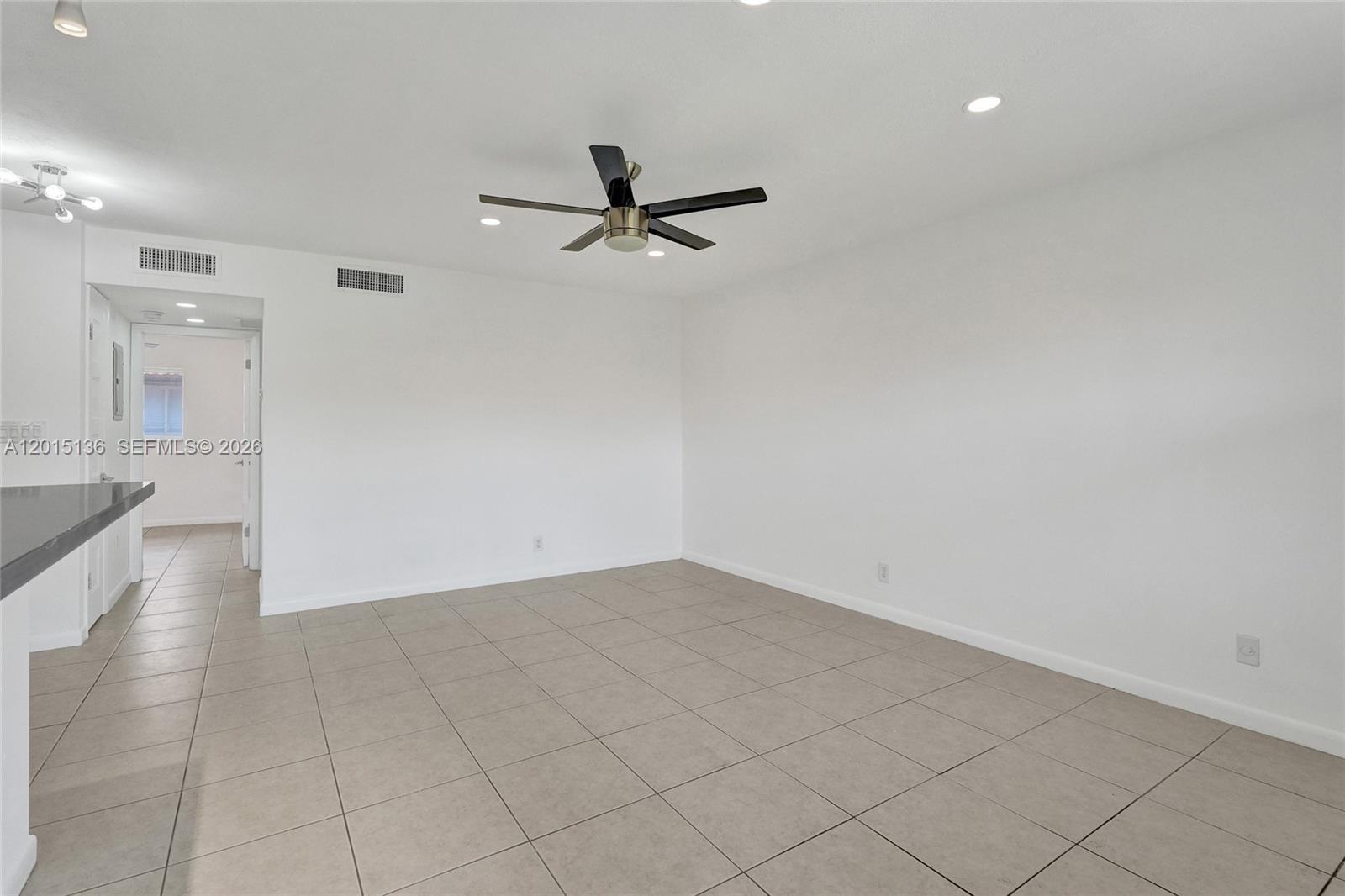 A bright, empty room features white walls, tile flooring, and a ceiling fan — 3050 NE 5th Ter # 13, Wilton Manors FL 33334, WILTON MANORS, FL