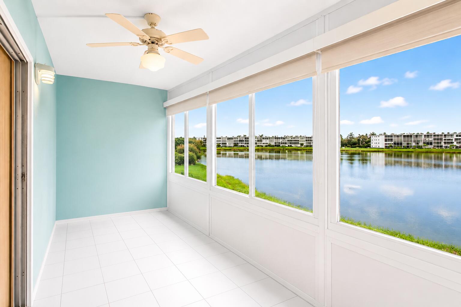 A sunroom with light blue walls, white tile flooring, a ceiling fan, and lake views — 3008 Cornwall A, Boca Raton FL 33434, BOCA RATON, FL