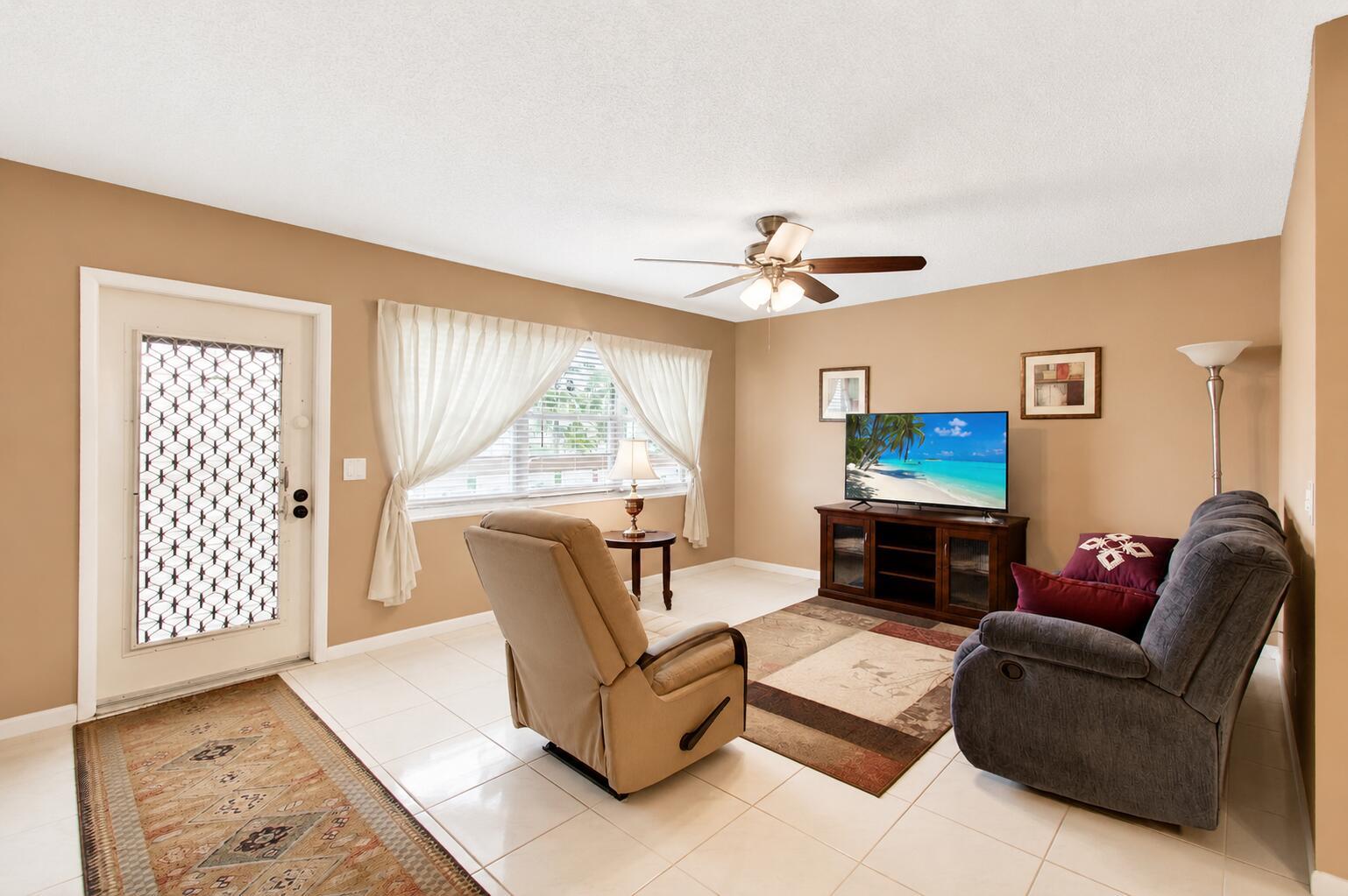 A living room features beige walls, tile flooring, a ceiling fan, and a television console — 3008 Cornwall A, Boca Raton FL 33434, BOCA RATON, FL