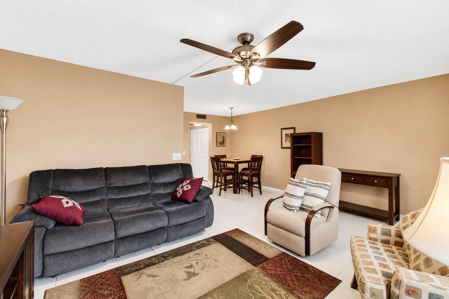A living room with a grey sofa, beige recliner, patterned armchair, and a dining area — 3008 Cornwall A, Boca Raton FL 33434, BOCA RATON, FL