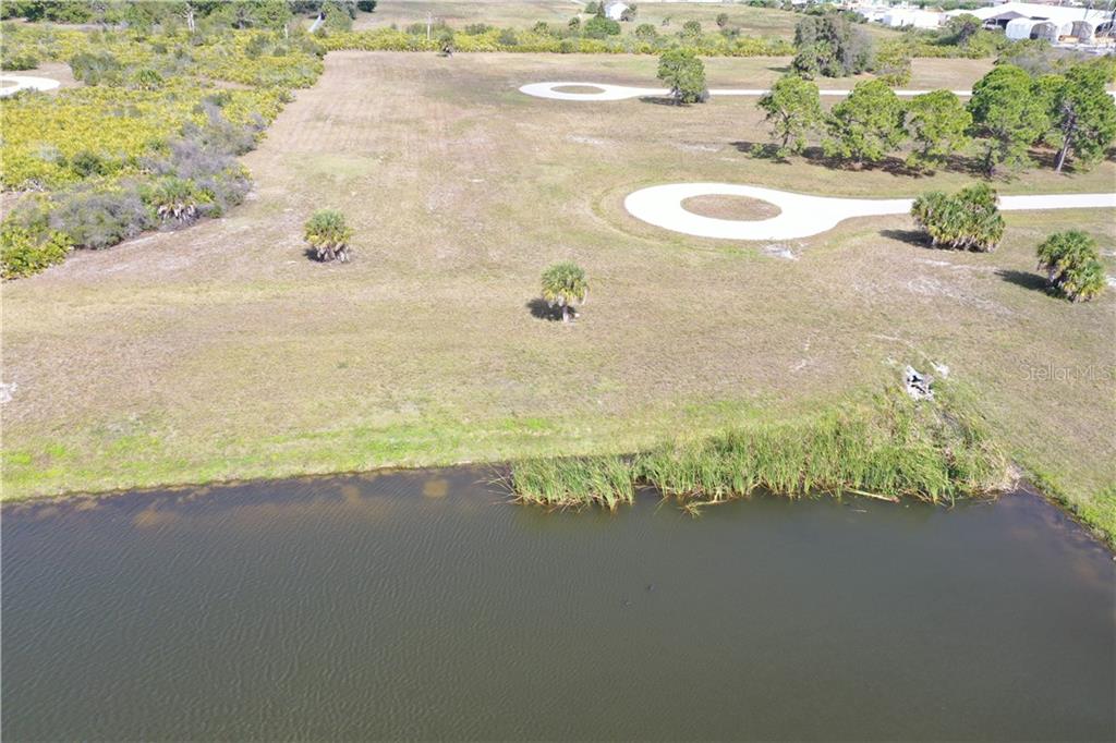 An aerial view shows a grassy lot with circular driveways next to a pond — 1 TARPON COURT, PLACIDA, FL
