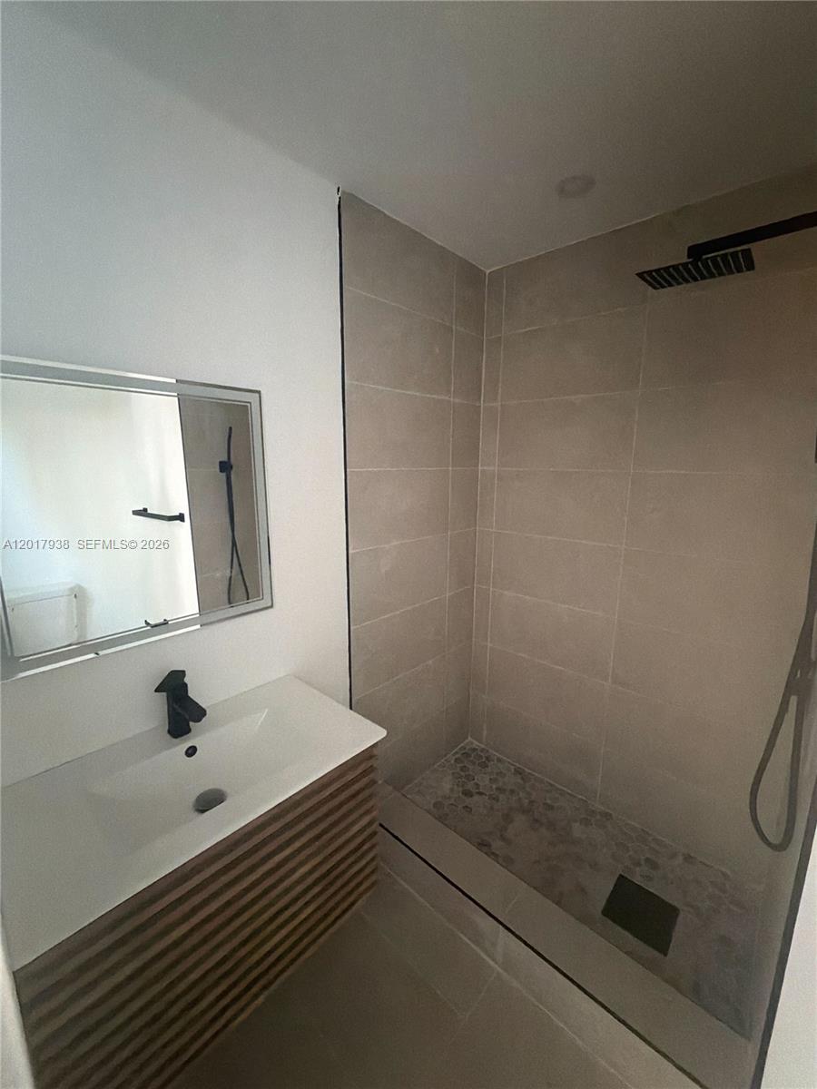 A modern bathroom features a floating vanity, a mirror, and a tiled walk-in shower — 7801 Byron Ave # B, Miami Beach FL 33141, MIAMI BEACH, FL
