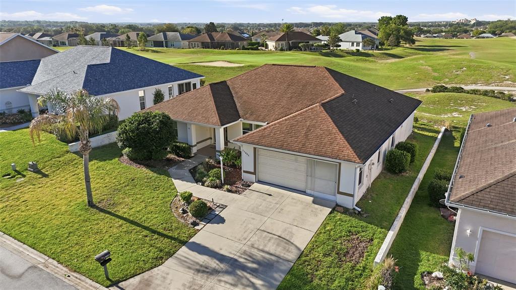 An aerial view shows a single-story house with a brown roof and a concrete driveway — 17083 SE 115TH TERRACE ROAD, SUMMERFIELD, FL