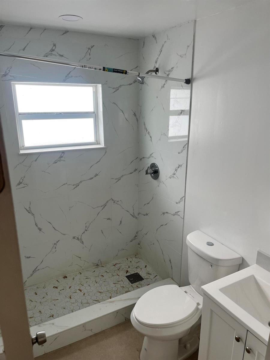 A bathroom features a walk-in shower with marble-look tile, a toilet, and a vanity — 701 S C Street, FL 33460, FL