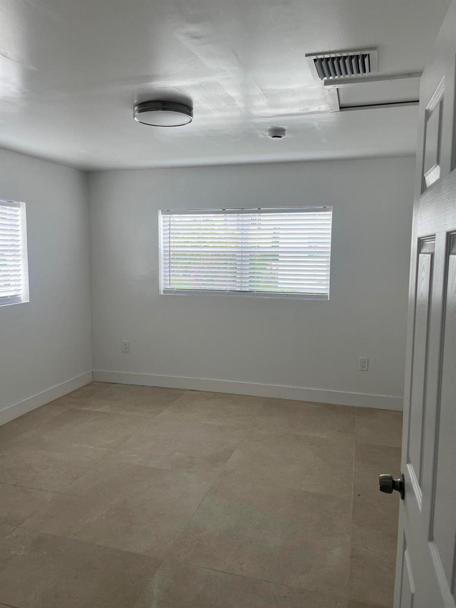 An empty room with white walls, tile flooring, two windows with blinds, and a ceiling light — 701 S C Street, FL 33460, FL