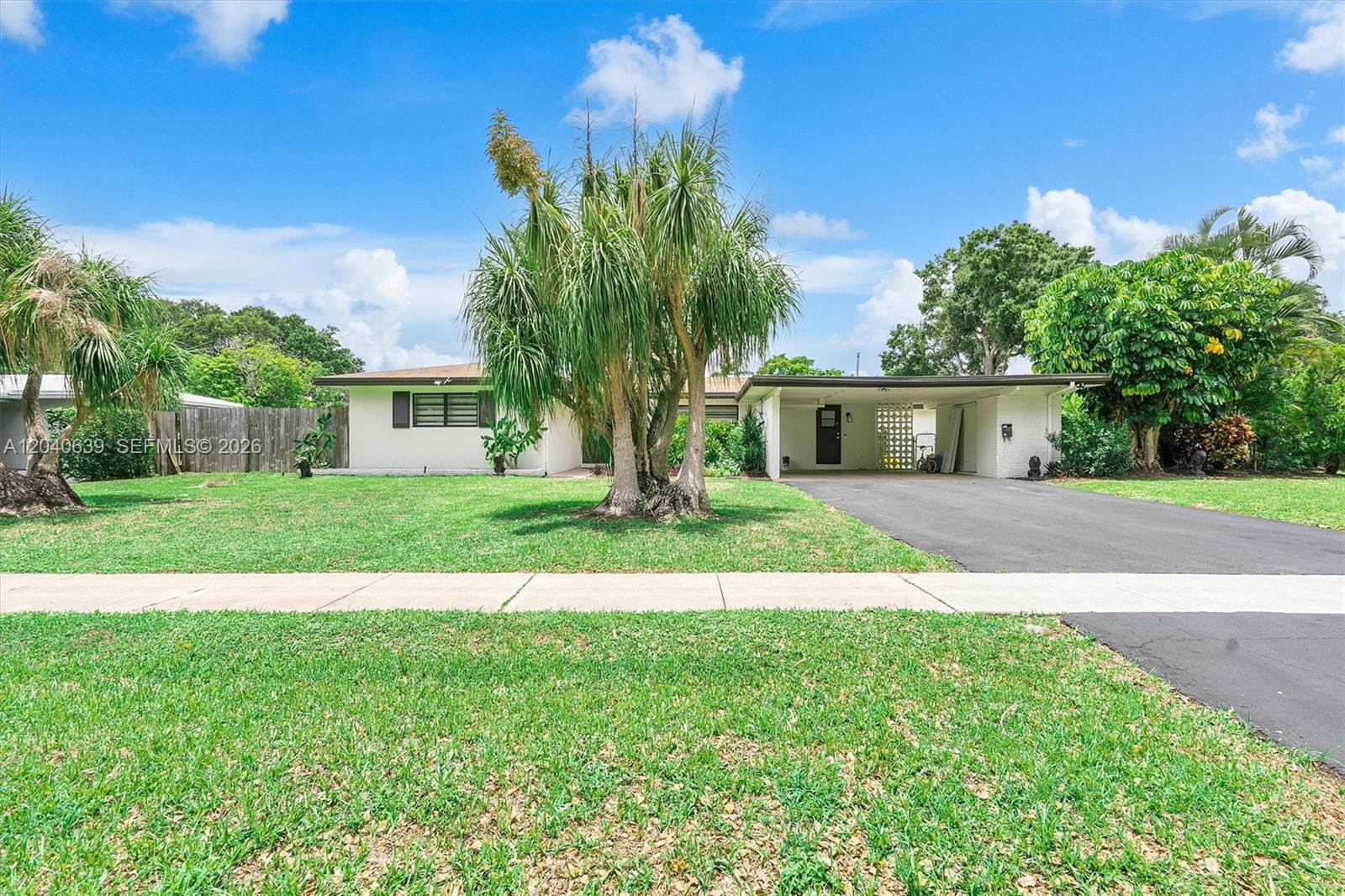 A single-story house features a white exterior, a carport, and a large palm tree — 885 Azalea Ct, Plantation FL 33317, PLANTATION, FL