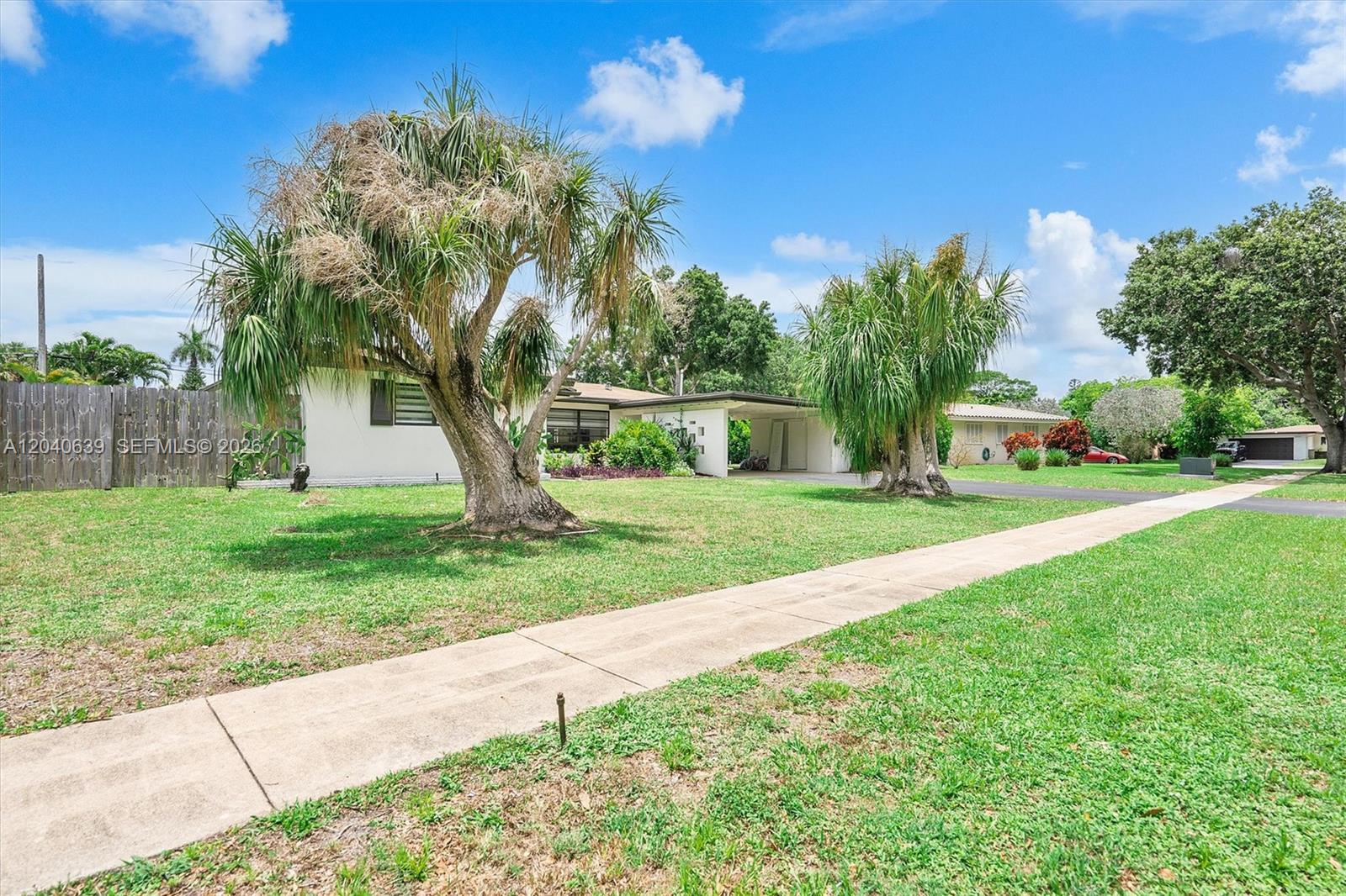A single-story house with a carport and palm trees sits behind a front lawn — 885 Azalea Ct, Plantation FL 33317, PLANTATION, FL