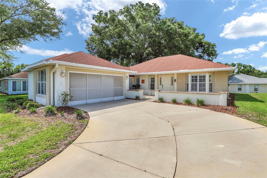 A single-story house with a red roof, beige siding, and a concrete driveway — 7279 SW 115 PLACE, OCALA, FL