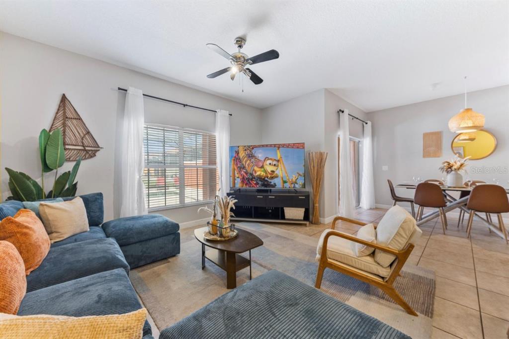 A living room features a blue sectional sofa, a television, and an adjacent dining area — 8847 CANDY PALM ROAD, KISSIMMEE, FL