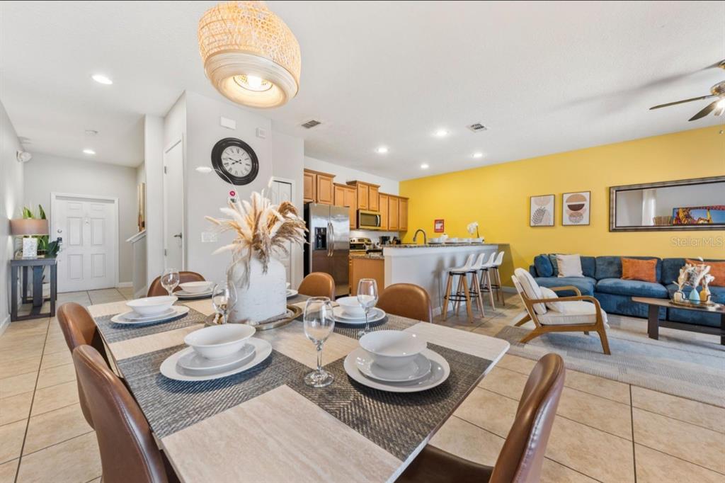 A dining area with a table and chairs opens to a kitchen and living room — 8847 CANDY PALM ROAD, KISSIMMEE, FL