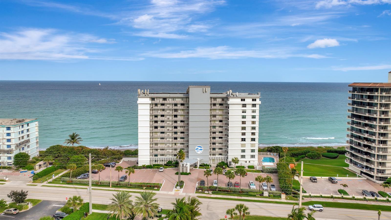 An aerial view shows a multi-story beachfront condominium building with a parking lot and ocean — 840 Ocean Drive # 806, Juno Beach FL 33408, JUNO BEACH, FL