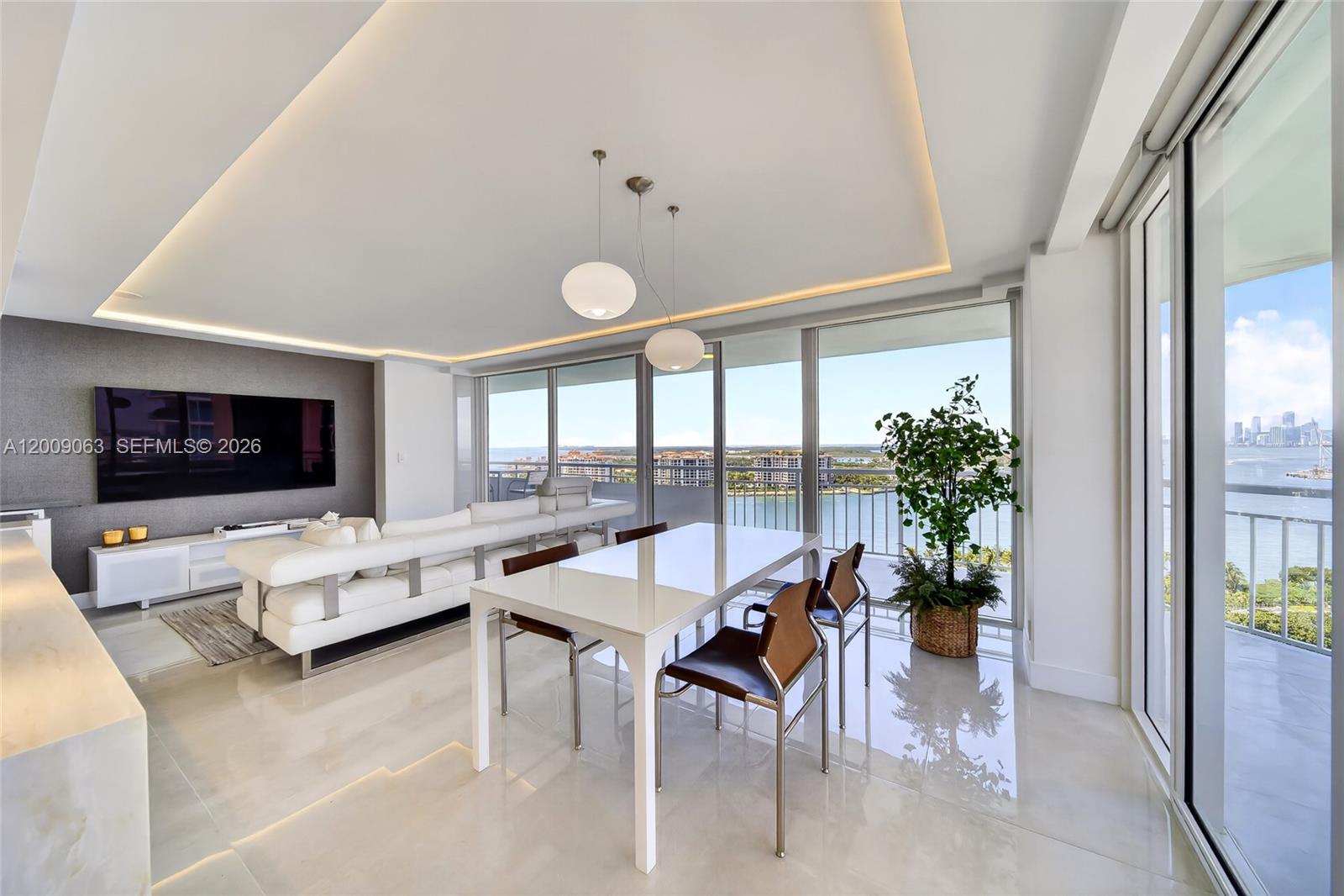 A modern living and dining area features white furniture, tile floors, and floor-to-ceiling windows — 400 S Pointe Dr # 2009, Miami Beach FL 33139, MIAMI BEACH, FL