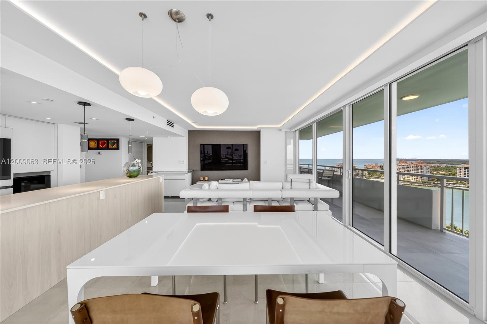 A modern living and dining area features a white table, sectional sofa, and balcony views — 400 S Pointe Dr # 2009, Miami Beach FL 33139, MIAMI BEACH, FL