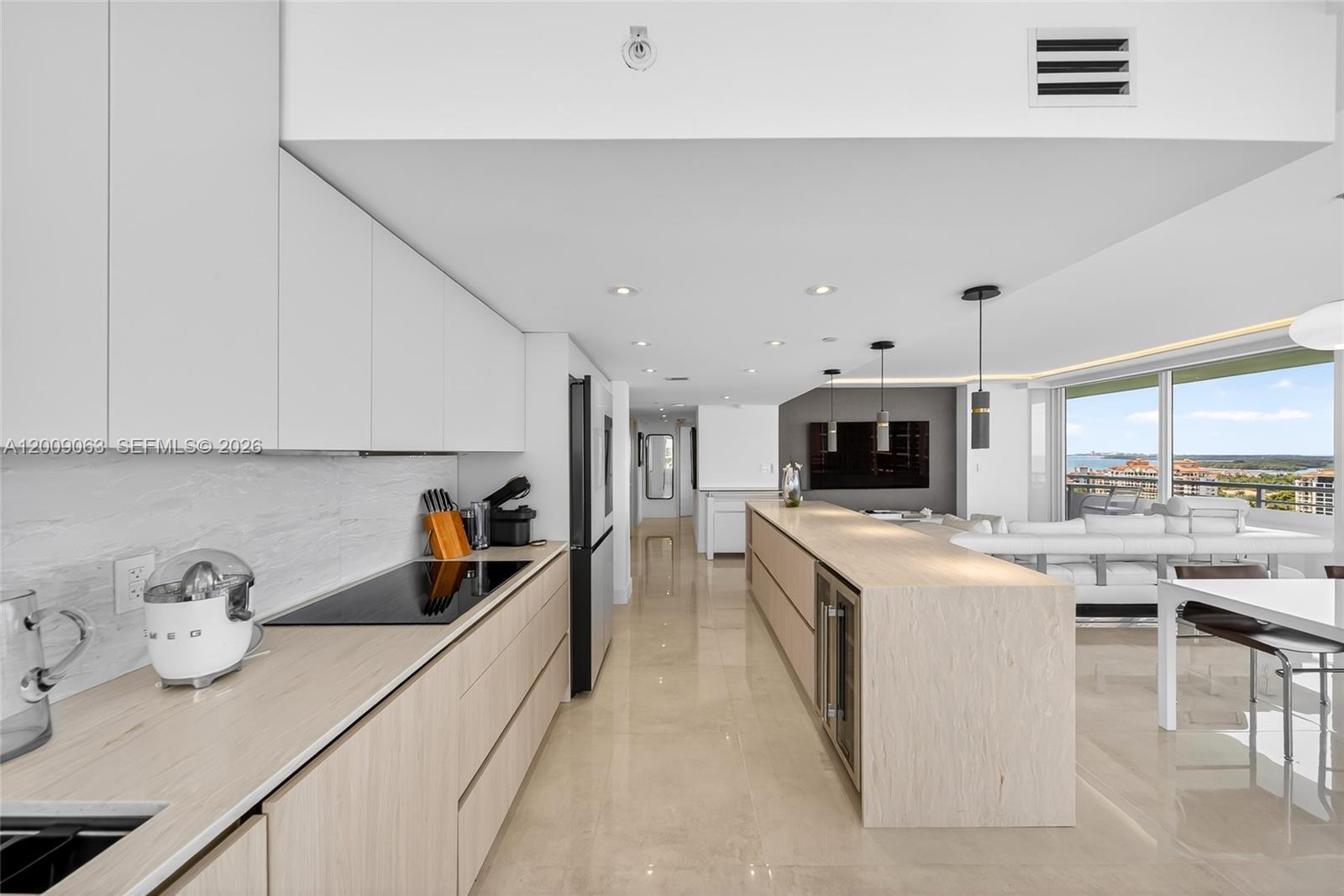 A modern kitchen features light wood cabinetry, a long island, and a view of the ocean — 400 S Pointe Dr # 2009, Miami Beach FL 33139, MIAMI BEACH, FL