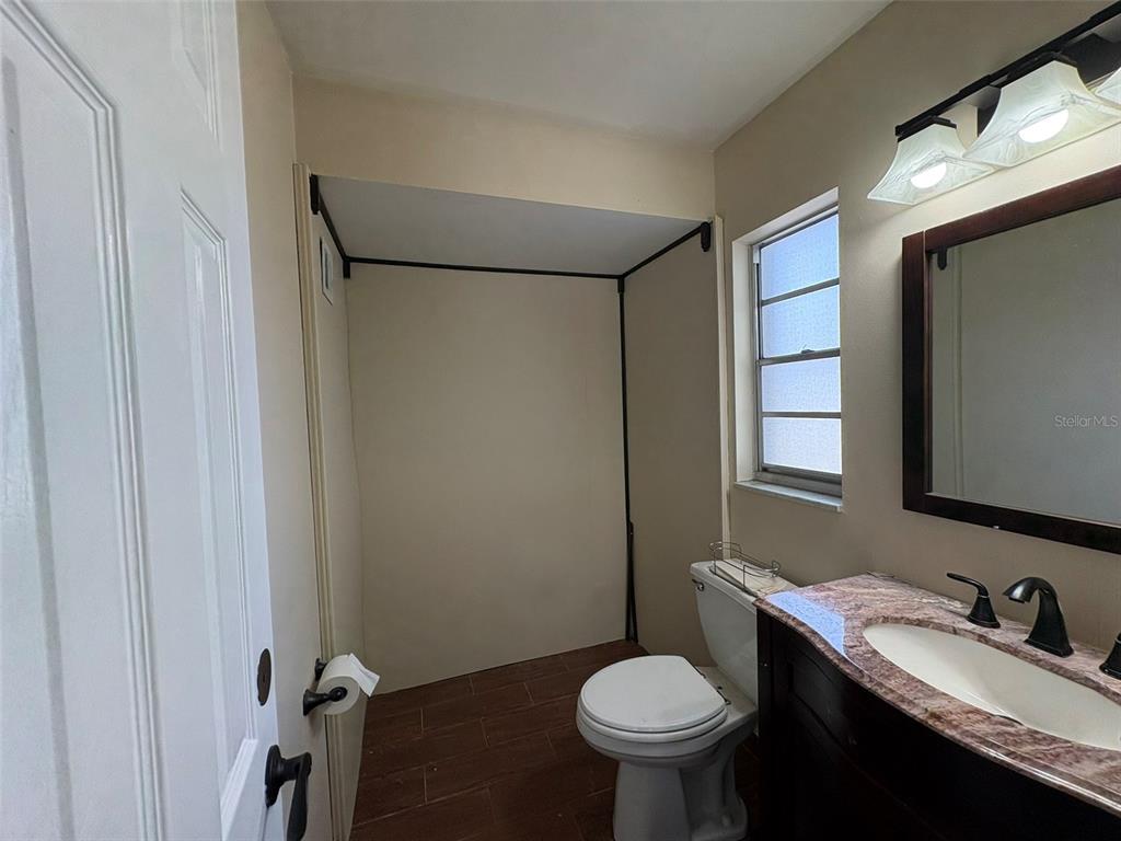 A bathroom features a toilet, a vanity with a stone countertop, and a shower area — 264 E ALTAMONTE DRIVE, ALTAMONTE SPRINGS, FL