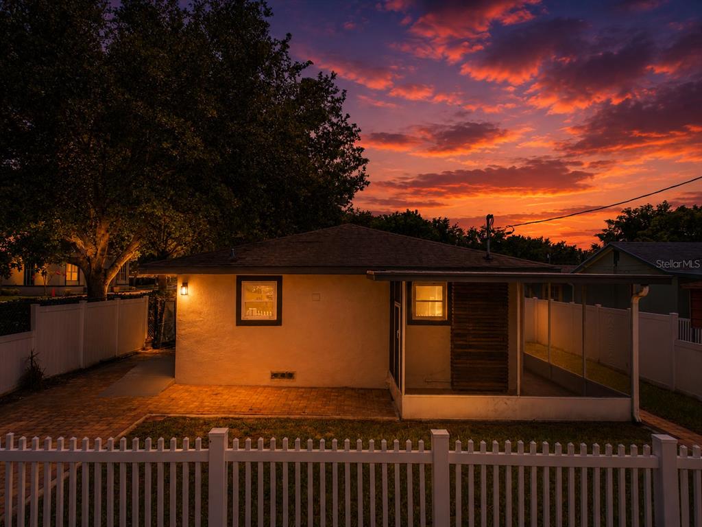 The exterior of a house at sunset features a paved patio and a screened-in porch — 1855 PROCTOR AVENUE, ORLANDO, FL