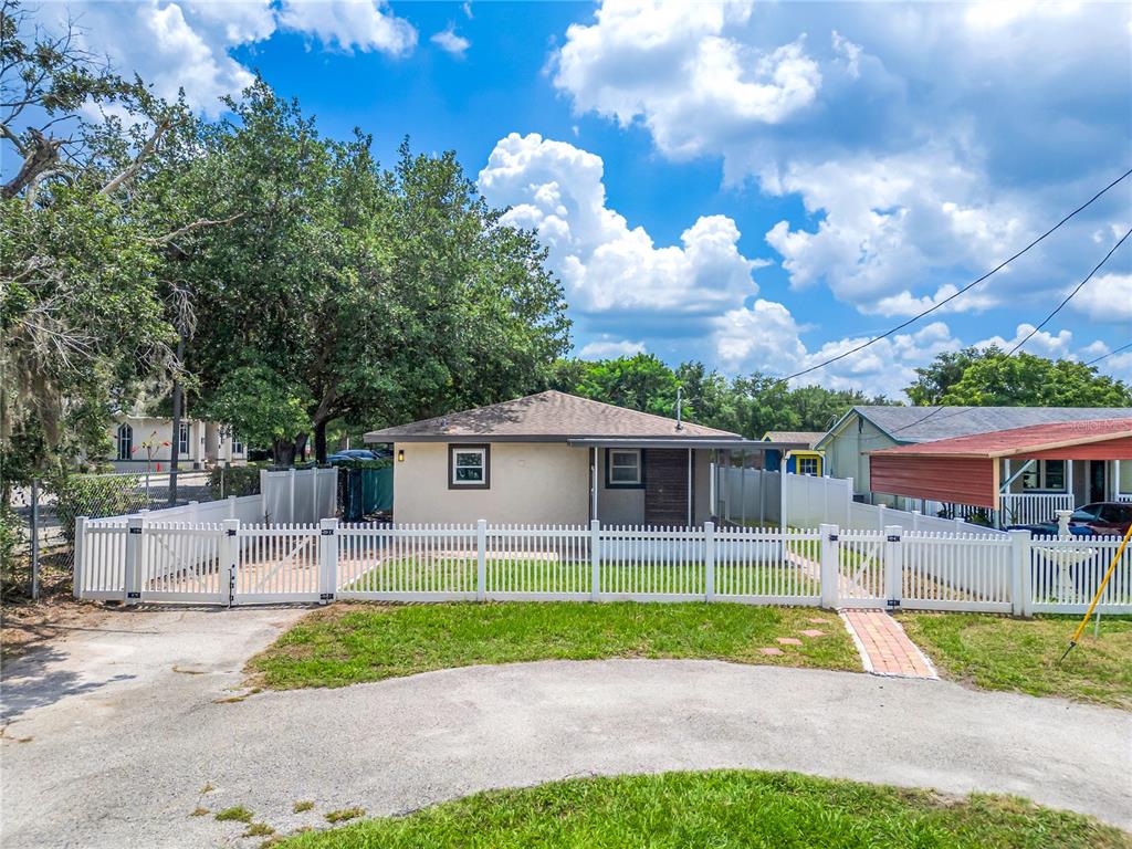 A beige house with a white picket fence and a large tree in the yard — 1855 PROCTOR AVENUE, ORLANDO, FL