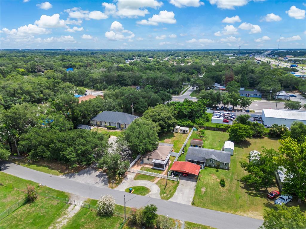 An aerial view shows several residential houses with driveways, trees, and a nearby road — 1855 PROCTOR AVENUE, ORLANDO, FL